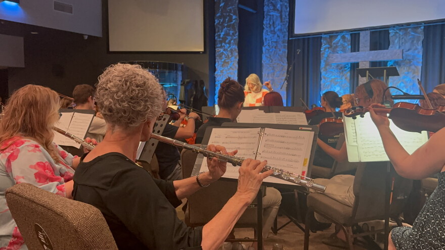 Several musicians playing various instruments, featuring a flutist. 