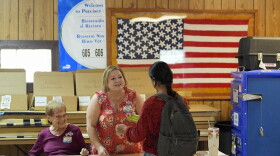 Poll worker hands a voter a ballot at a polling station inside the American Legion in South Miami, Fla.