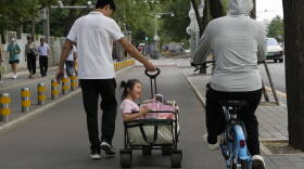 A child is pulled in a trolley in the afternoon in Beijing, Thursday, July 20, 2023. (Ng Han Guan/AP)