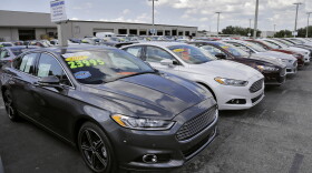 A car salesman works the telephone while searching through inventory at the certified used car lot at Brandon Ford in Brandon, Fla.
