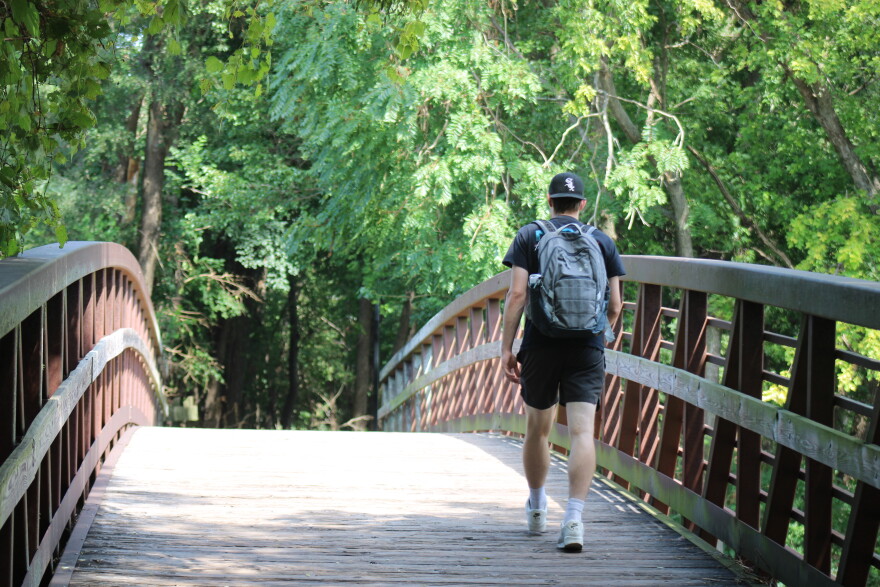 Man in backpack walks across bridge.