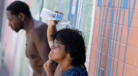 People, who are homeless, try to cool down with chilled water outside the Justa Center, a day center for homeless people 55 years and older. (Matt York/AP)