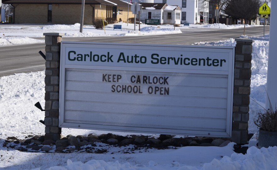 A white sign says, "Keep Carlock School Open."