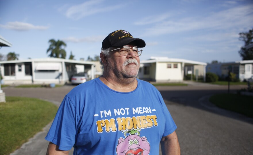 Daniel Clearwater stands in front of his home in Pinellas Park, Florida. He wears a "I'm not mean; I'm honest" shirt. 