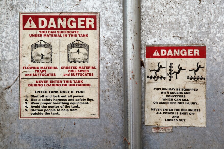 Red and white signs titled 'Danger' detail the risks of suffocation and injury when entering grain bin