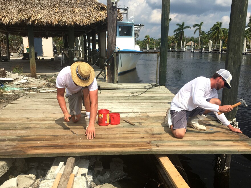 In Everglades City, Fla., crab fishermen Shane Reamao, left, and Dalton Daffin hurry to repair a commercial fishing dock that was destroyed during Hurricane Irma.