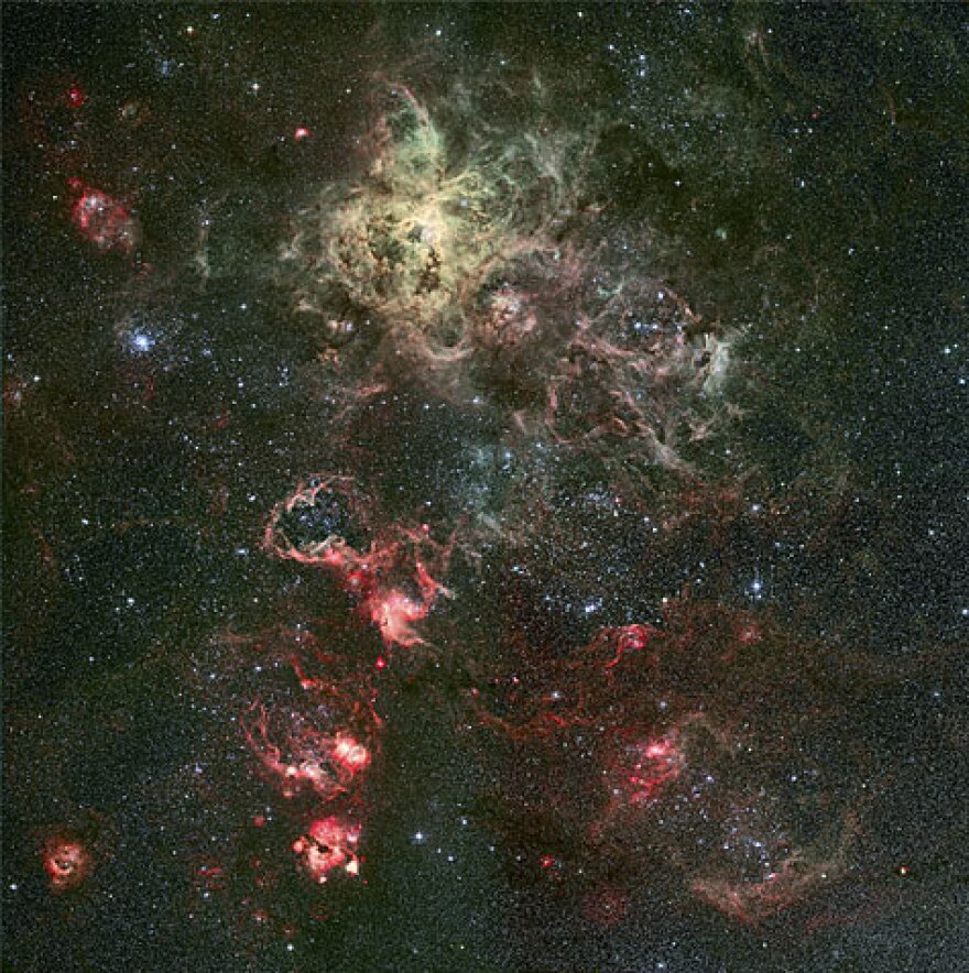 This image of the Tarantula Nebula and the area around it was taken with a 2.2-meter optical telescope in La Silla, Chile. The spider-web look gives the nebula its name, which is seen in the upper-center of the image. Slightly to the lower-right, a web of