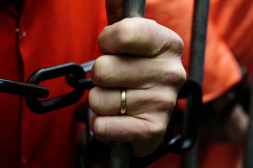 Married prisoner holding prison bars.