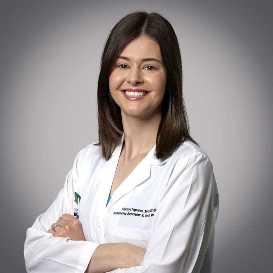 a woman in a white medical coat smiles at the camera