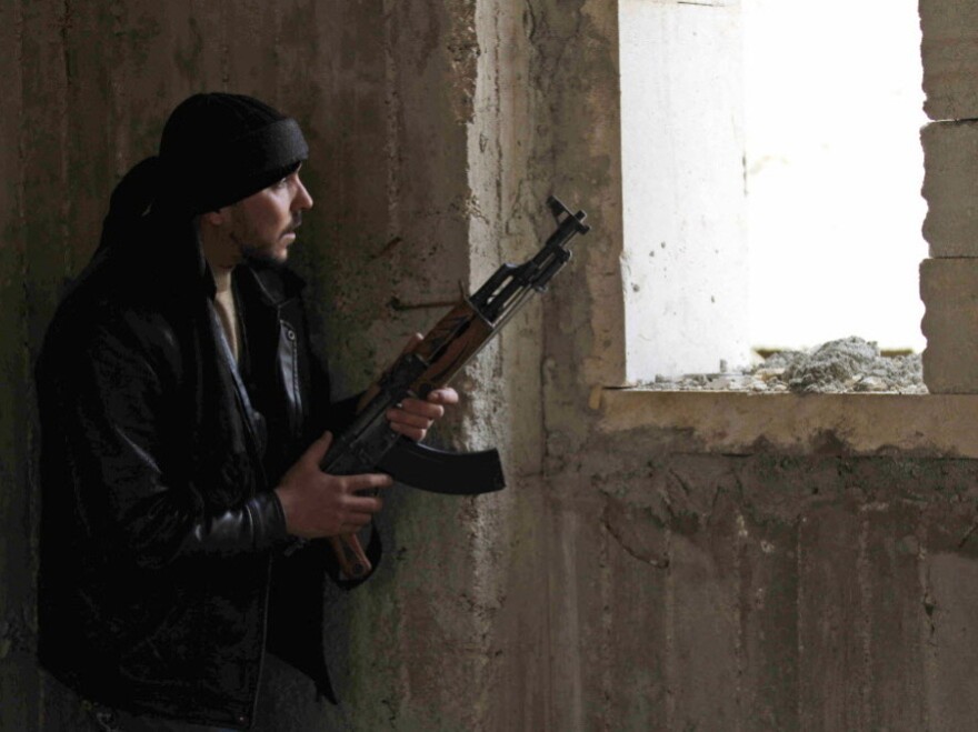 An anti-regime fighter peered  through a window in Idlib, Syria, on Thursday (Feb. 9, 2012).