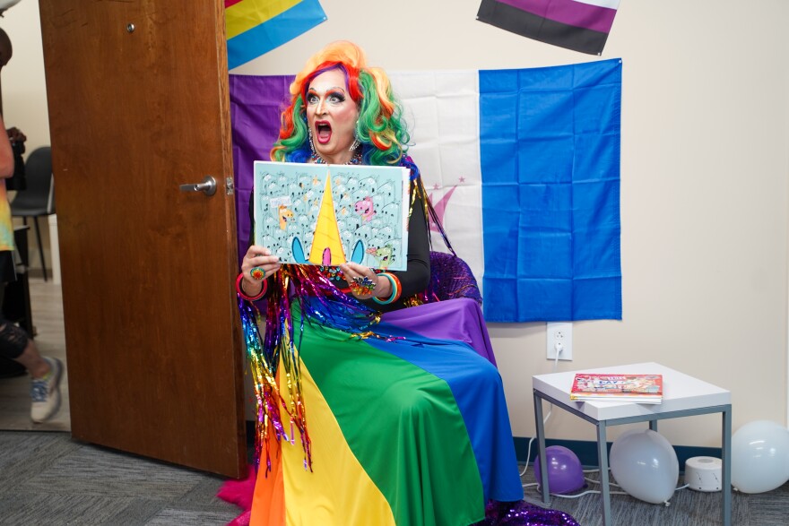 drag queen reads book and crosses her eyes making a face