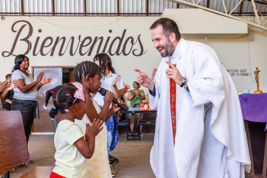 The Rev. Brian Strassburger smiles as Alcala Bouilly sings into the microphone during Mass at Casa del Migrante on Thursday, March 19, 2026, in Reynosa, Mexico.