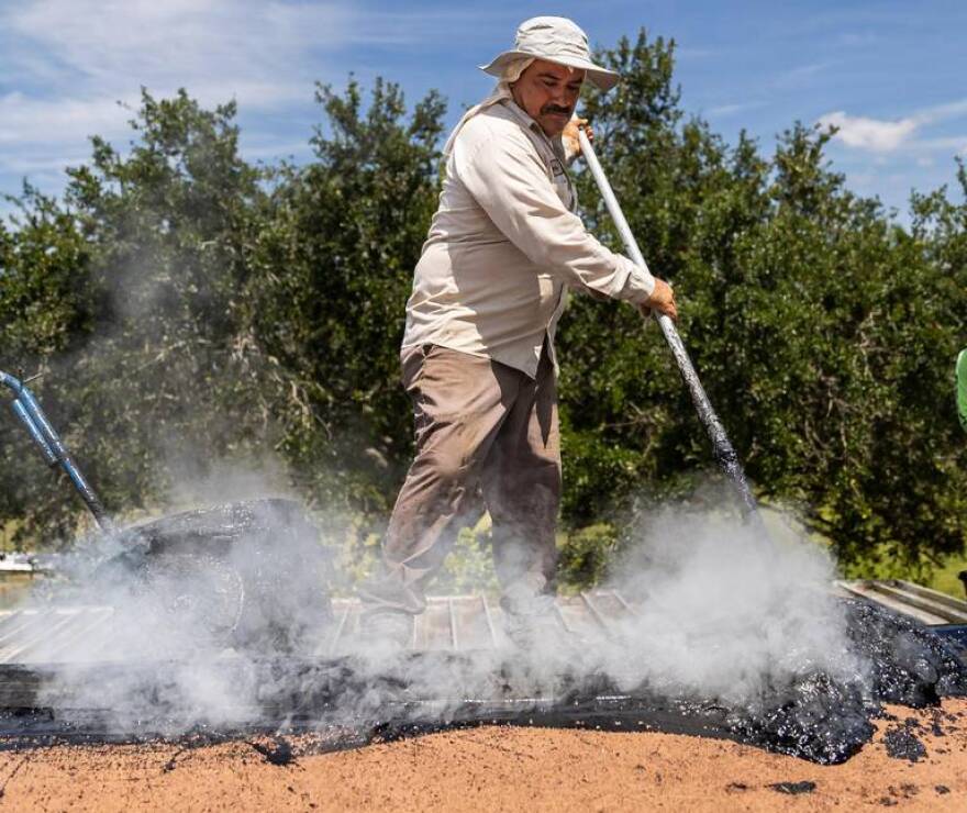 Gilberto Lujano, 49, spreads tar while working on a roof on Tuesday, May 2, 2023, in Homestead, Fla.