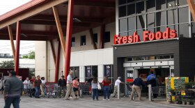 A long line of customers waited for an Austin store to open the morning after the city ordered restaurants to close and offer takeout service only. 