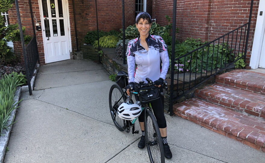A photo of Leta Highsmith standing next to a bicycle in front of a brick building