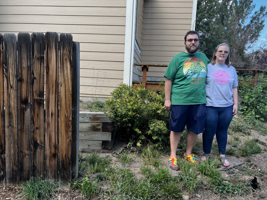 Katie Svoboda-Rini and her husband Nate stand near the remainder of the wood fence that used to enclose their backyard in Superior. The family hopes to rebuild it in a fire-resistant material but may be limited by homeowner association requirements.