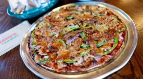 A “Deluxe” St. Louis-style pizza topped with sausage, mushrooms, onions, green pepper, bacon, and Provel cheese alongside toasted ravioli and a house salad on Thursday, Oct. 6, 2022, at Imo’s Pizza in St. Louis’ Downtown West neighborhood. (Brian Munoz/St. Louis Public Radio)