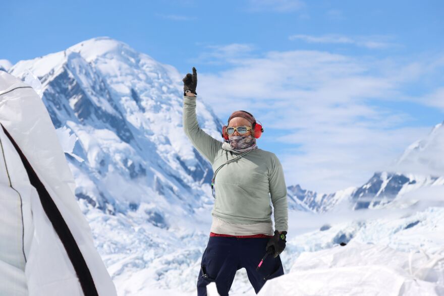 Cecelia Mortenson signals to a helicopter pilot who was working to pick up a large sling load of gear headed back to Yakutat.