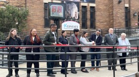 City officials and relatives of Leo Ferris and Danny Biasone cut the ribbon on the new location of the shot clock behind them.