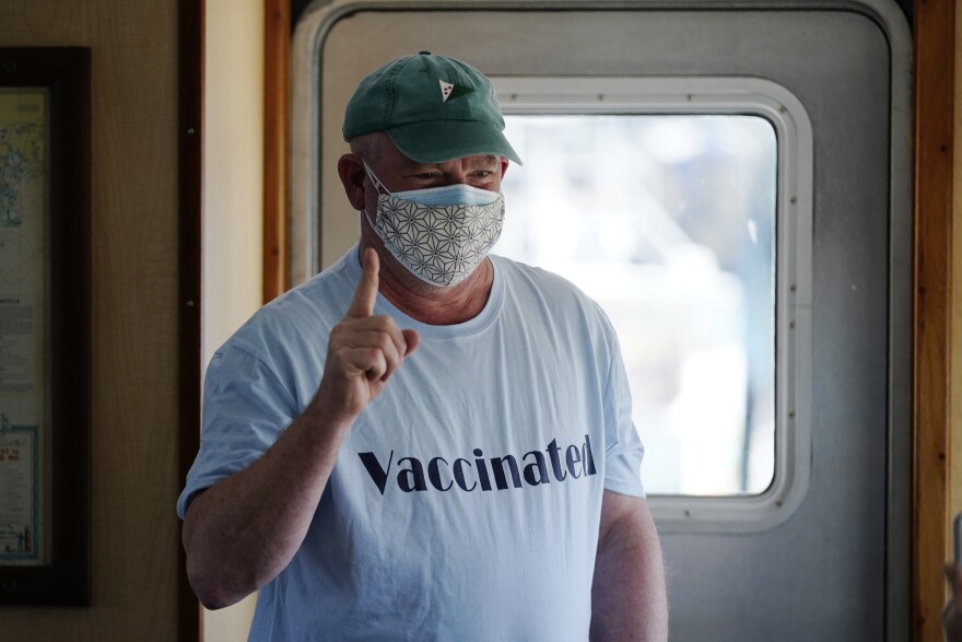 FILE-In this Friday, March 19, 2021, file photo, Jonathan Partin wears an appropriate tee-shirt as he celebrates receiving a COVID-19 vaccination aboard the Sunbeam in Northeast Harbor, Maine. The Sunbeam is a 74-foot vessel operated by the non-profit Maine Seacoast Mission. The mission has vaccinated hundreds of people who reside on Maine islands.