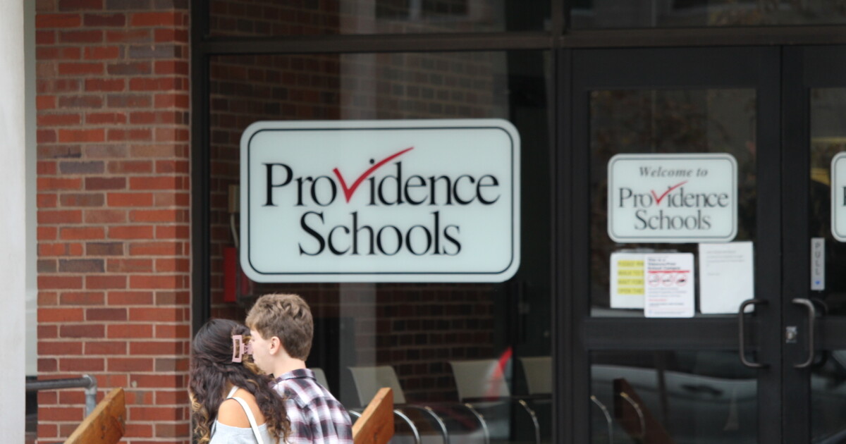 Students walk past a Providence Public Schools sign. The district continues to struggle with low reading and math scores as questions about its leadership emerge after seven years of state control. Credit: Ben Berke/Ocean State Media