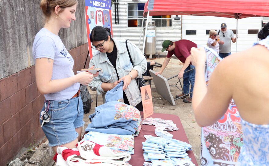 Vendor stands behind booth selling merchandise.