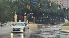 A car splashes its way down Houston Street downtown on Oct. 1, 2026