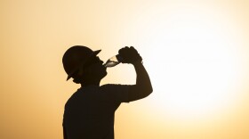 A U.S. airman drinks water while working on a construction site in extreme heat in Southwest Asia, 2017.