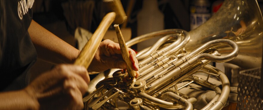 hands repair a french horn