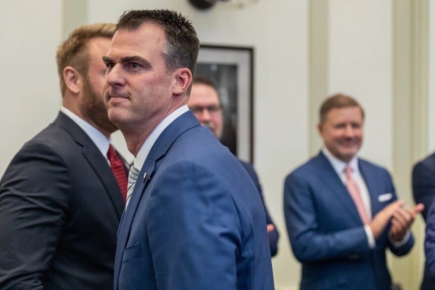 Kevin Stitt (center) makes his way past an applauding Attorney General Gentner Drummond (right) at the 2023 State of the State Address.