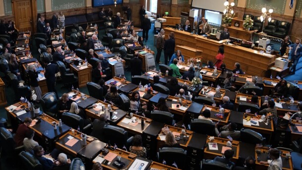 Colorado state representatives sit at their desks in the statehouse in a view taken from the balcony.