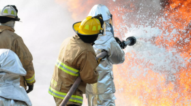 Firefighters blast a stream of aqueous film-forming firefighting foam in a training event. The foam contains PFAS, a substance that causes serious human health problems.