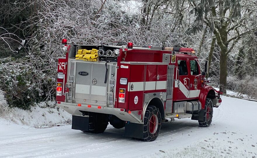 A fire truck with chains on the tires is on a snowy street