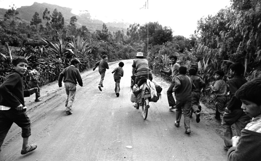 Peruvian schoolboys run alongside June Siple’s bike as she and Greg Siple head out of Ayacucho, Peru. As one of only two times on the Hemistour that they were stopped by weather, they were stuck there for several days due to wintery conditions at higher altitudes.