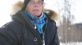 a woman in outdoor gear, with headphones hanging from her jacket