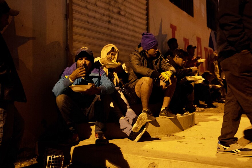 Migrants eat under the orange hue of a blinking street light. The gallons of stew are gone in a heartbeat. Even though they fed hundreds that night, Lilian Mejía can't help but tear up when she announces the food's gone to those who didn't get any. "They're so hungry, you just want to feed all of them but it's impossible," she says.