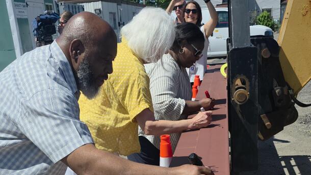 Members of the BPS board sign the final steel beam to be placed in construction of the school district's commissary.