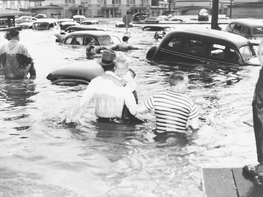 Two men struggle through waistdeep water in the inundated community of Vanport, Ore. on May 30, 1948 with a child, following a break in a dike which allowed water of the Columbia River to sweep through the town.