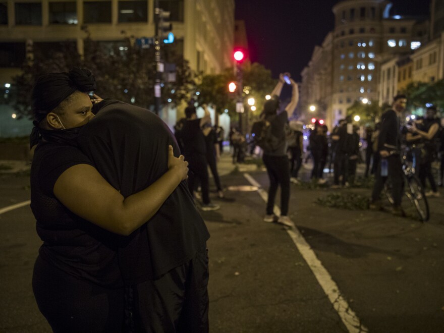 F and 5th streets NW, when a helicopter hovered above the group of protesters causing them to stop and brace against the wind in Washington, D.C. on Monday.