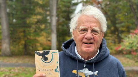 Author Michael Delp poses with a copy of his new book, "Of Blood and Rivers," a collection of elegies about grief and loss. (Photo: Ed Ronco/IPR News)