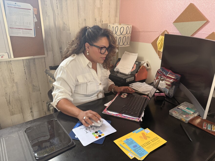 A woman sits at a desk typing on a laptop