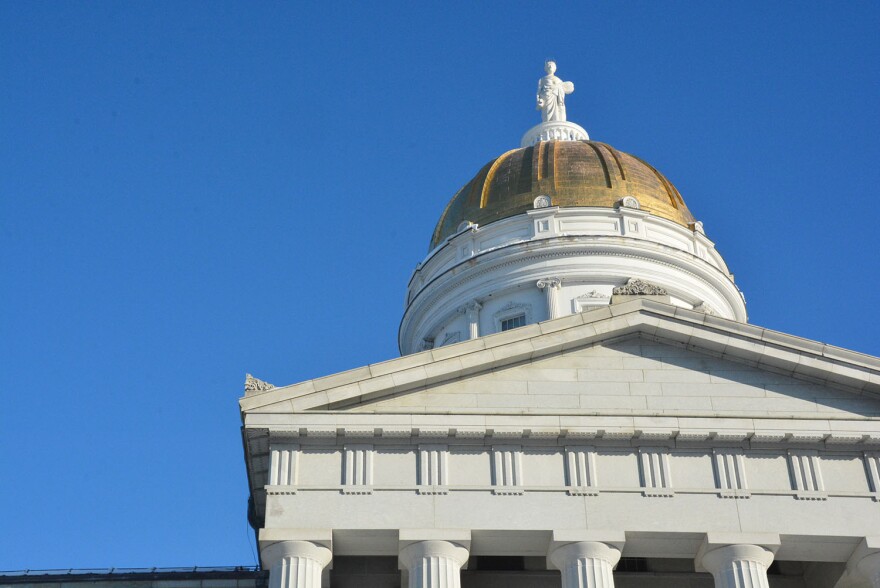 The golden dome of the Vermont Statehouse with a blue sky background.