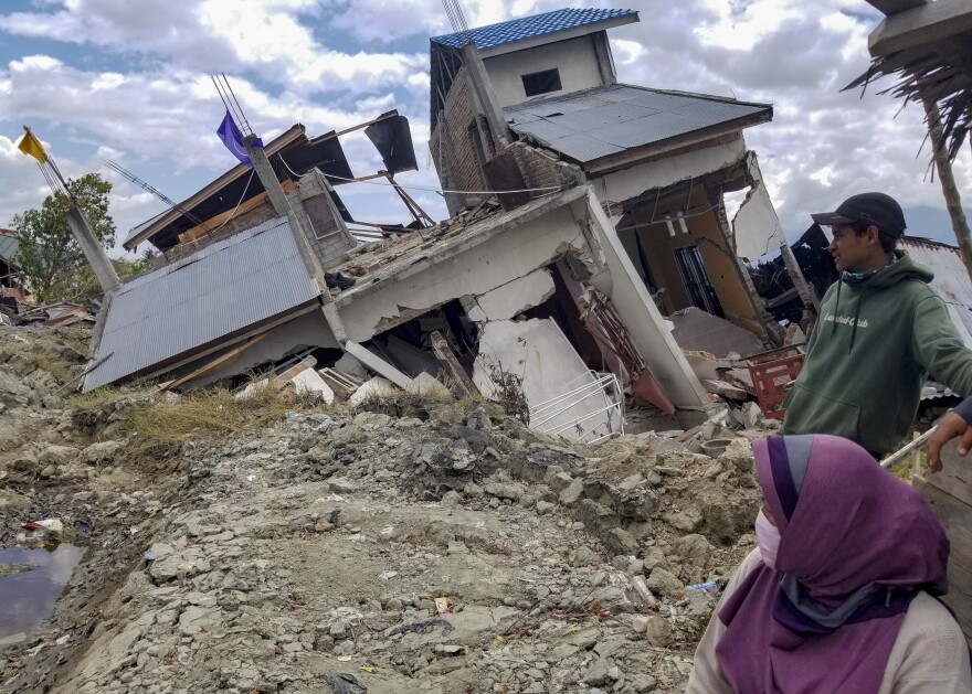 Vera Rahayu Putri and her husband Faizal, who goes by one name, survey earthquake damage in their Palu neighborhood of Petobo, now covered by mudslides. Putri's 9-year-old son, Raldi, is among thousands of children who are unaccounted for.