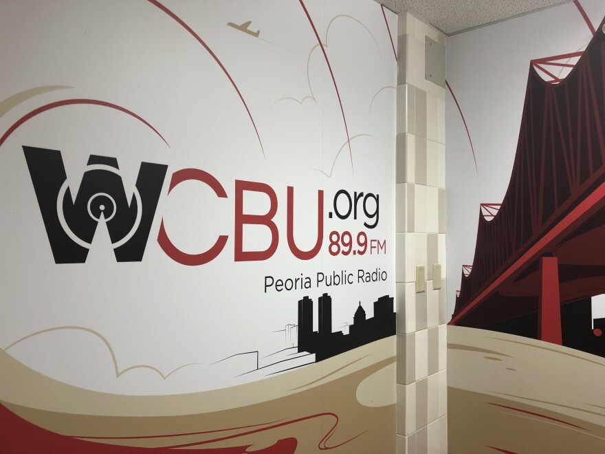 A mural in the entry hallway at the WCBU newsroom in Morgan Hall on the Bradley University campus shows the station's branding logo and depictions of the Peoria skyline and the Murray Baker Bridge. 