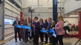 Albany High School junior Simon Carey cuts the ribbon at an unveiling ceremony for the school automotive program's new Subaru.