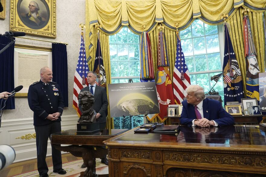 President Donald Trump and Rep. Jim Banks, R-Ind., listen as Space Force vice chief of space operations Gen. Michael Guetlein speaks in the Oval Office of the White House, Tuesday, May 20, 2025, in Washington.