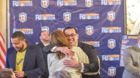 General Treasurer James Diossa shares a hug ahead of a press conference detailing the state’s plans to accommodate international travelers who will visit New England this summer for the 2026 FIFA World Cup.