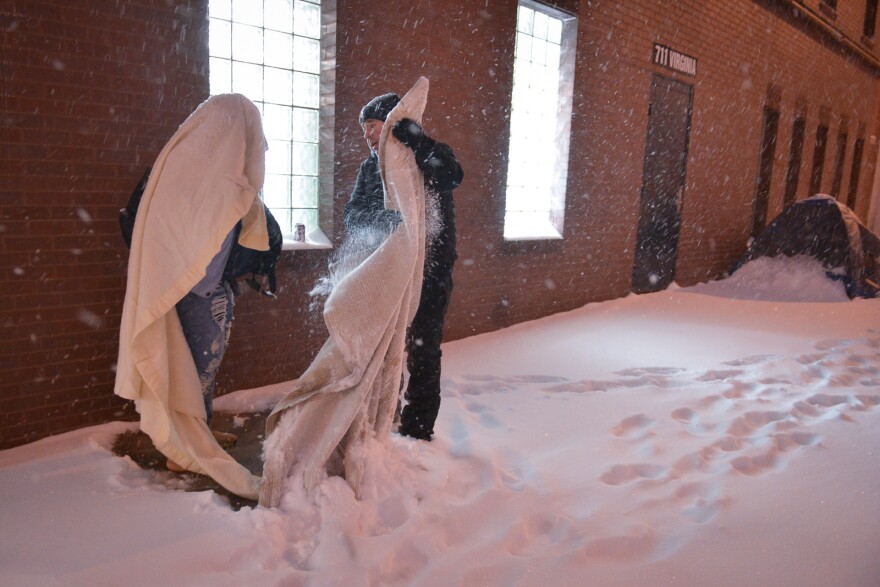 Hope Faith Homeless Assistance Campus Executive Director Doug Langner helps a woman get up out of the snow where she slept Wednesday morning.