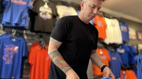 Alma Mater Custom Apparel owner Brian Meade folds Gators polos ahead of Labor Day weekend. He’s increasing the store’s stock and extending the hours of operation to prepare for more business. (Jeffrey Serber/WUFT News)