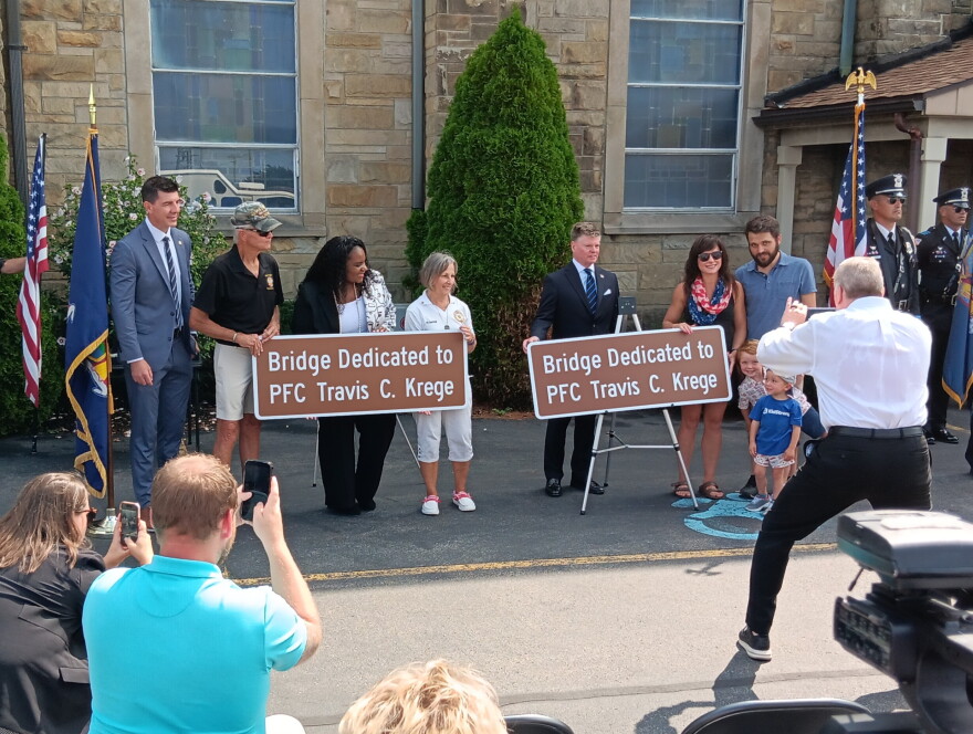 State Assemblyman Patrick Chludzinski, State Senator April Baskin, Thruway Authority Executive Director Frank Hoare and members of the late Travis Krege's family stand with copies of the sign now dedicating the Cleveland Drive Bridge in his memory.